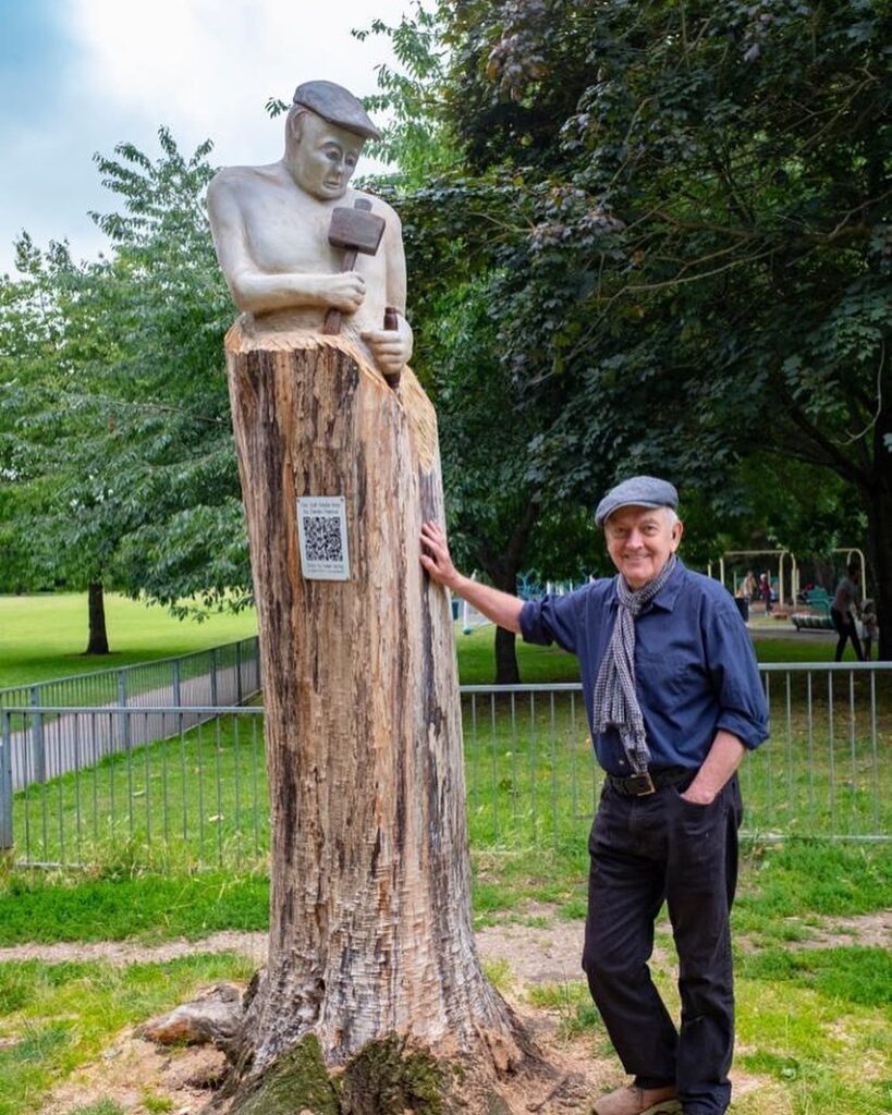 Derek Pearce standing with his statue "Self made"